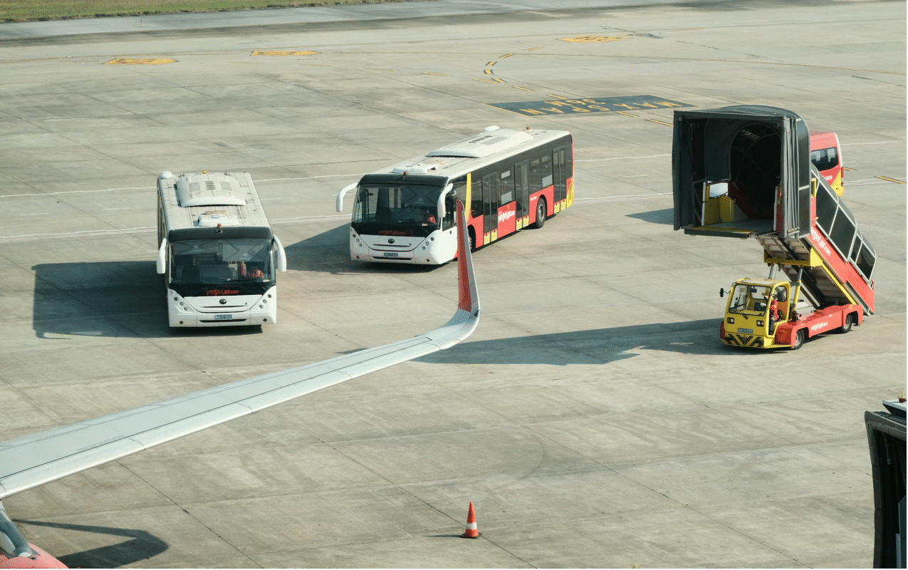 Airport tarmac with shuttle buses and a baggage loader.