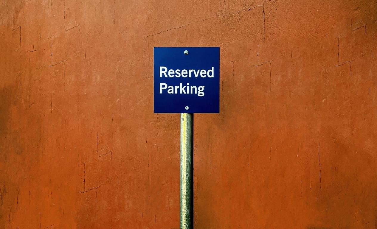 Reserved parking sign on an orange wall.