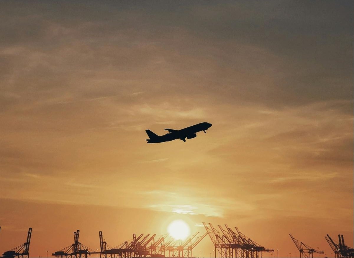 Aeroplane flying in early-morning sky at sunrise.