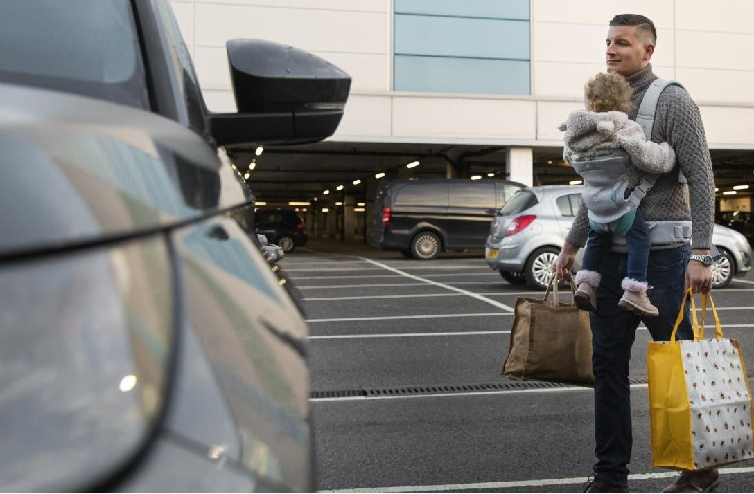 Person with a child and luggage at airport parking.
